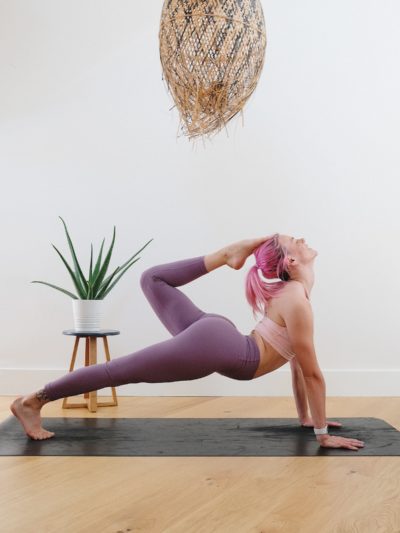 Woman doing yoga stretched out with a leg bent backwards touching her head